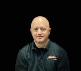 Male owner with no hair sitting with a black background